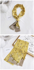 Detail of a ginger silk scarf with white floral patterns and taupe contrast edges