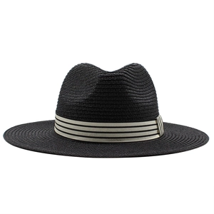 Close-up of a black straw fedora hat featuring a stylish black and white striped ribbon