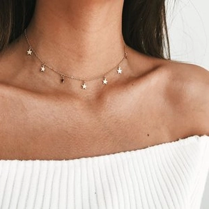 Close-up of a gold choker necklace with delicate star charms on a female model