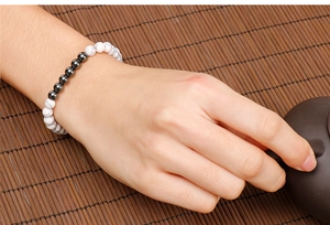 Detail of white turquoise and black stone beaded bracelet worn on wrist with zen background