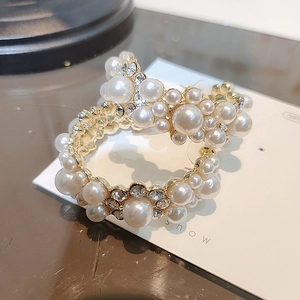 Elegant gold-tone C-shaped hoop earrings with pearls and rhinestones on a display card
