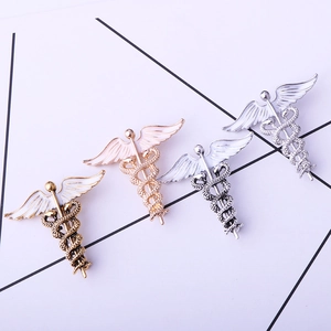 Detailed view of medical Caduceus snake brooches in gold, rose gold, silver, and antique finish