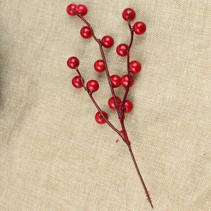 Close-up of red artificial Christmas berries on stems over beige rustic linen texture