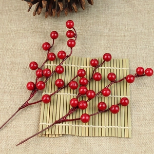 Close-up of vibrant red artificial berry branches on a rustic bamboo mat for Christmas