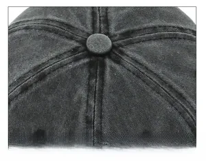 Close-up of top stitching and fabric-covered button on a washed denim baseball cap