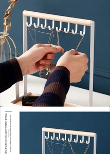 Close-up of white iron jewelry stand with eight J-hooks and natural wood tray details