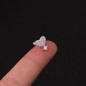 Macro shot of a silver heart stud earring with pavé stones held on a fingertip
