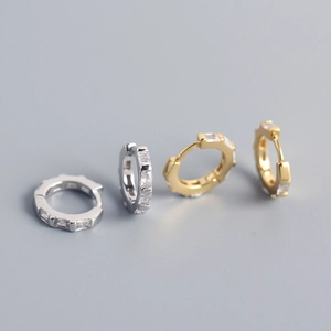 Macro detail of geometric silver and gold hoop earrings with rectangular zircon stones