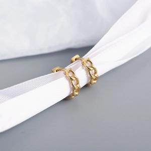 Macro detail of gold chain link hoop earrings with silk ribbon on grey background