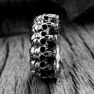Macro shot of vintage stainless steel punk ring with 3D embossed skull reliefs on dark wood