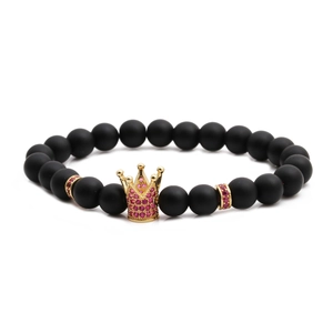 Close-up of matte black beaded bracelet featuring a gold crown with pink zircons