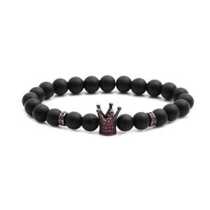 Macro shot of matte black stone beads with crown charm pavé set with pink crystals