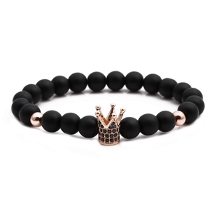 Detailed view of matte black stones and rose gold crown charm on a beaded bracelet