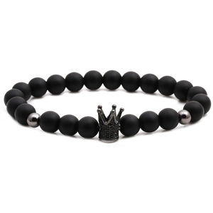 Macro detail of matte black stone bead bracelet with crown charm and metal accents