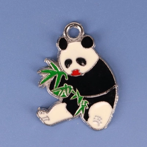 Macro shot of an alloy panda eating bamboo charm with green enamel on blue background