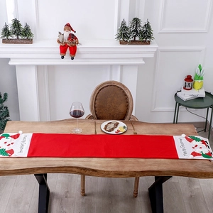 Red and white Christmas table runner with Merry Christmas embroidery on a wooden table