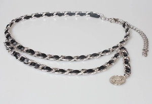 Macro detail of silver metal chain interwoven with black leather and coin charm