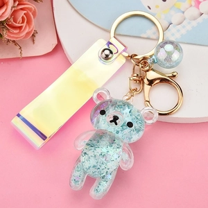 Macro shot of a blue liquid glitter bear keychain with laser strap and golden ball charm