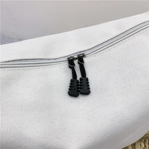 Close-up of durable black zipper with non-slip texture on white canvas messenger bag