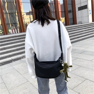 Outdoor shot of the large black canvas crossbody bag showcasing its casual draped fit