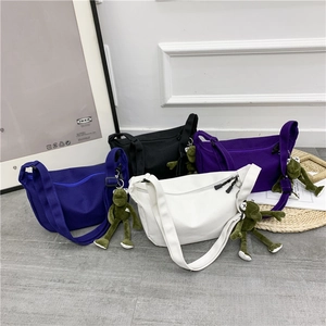 Detail of multi-color canvas crossbody bags with plush frog charm and zip closure