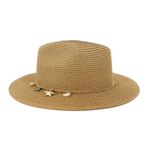 Detalle de sombrero de paja con cadena dorada y dijes de estrella de mar y concha