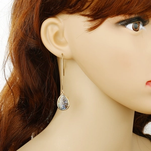 Close-up of teardrop shell earrings in gold on a model profile to show scale and texture