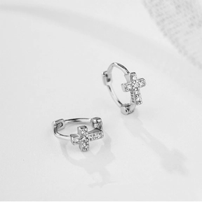 Macro shot of S925 sterling silver stamp and sparkling pave cross pendant on hoop earring