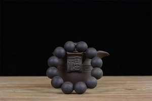 Detailed macro view of raw African Blackwood beads paired with a traditional clay teapot