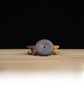 Detailed macro view of 50mm ebony wood Ping'an buckle showing natural grain on wooden stand