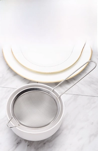 Vue détaillée de la passoire en acier inoxydable à maille fine sur un bol en porcelaine
