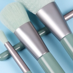 Close-up of mint green bristles and silver metal handles on a mini makeup brush set