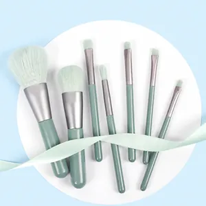 7-piece mini makeup brush set with green handles and gradient bristles on blue background