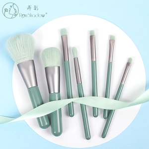7-piece mini makeup brush set with green handles and gradient bristles on blue background