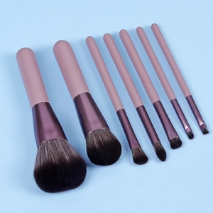 Detail of 8 pink makeup brushes with dark purple ferrules on a light blue background