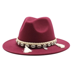 Detail of burgundy wool fedora featuring shell accents and ethnic tassel band