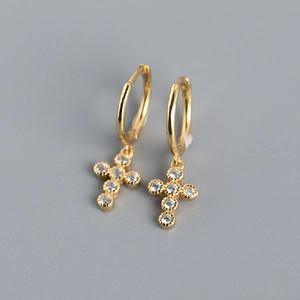 Macro shot of gold cross hoop earrings with sparkling cubic zirconia on gray background