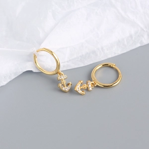 Close-up of gold-plated silver anchor earrings featuring clear diamond accents on a ring