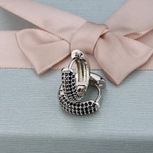 Close-up of black zircon pavé hoop earrings on a light blue ribbon gift box