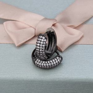 Macro shot of black plated huggie earrings with white zircon pave setting on blue background