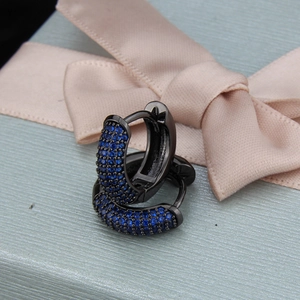 Detail of black hoop earrings with blue zircon stones on a gift box and satin ribbon