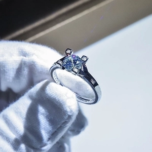Macro shot of silver ring with large square-cut diamond and pavé side stones on white glove