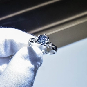 Close-up of elegant moissanite ring with twisted band held by white gloved fingers
