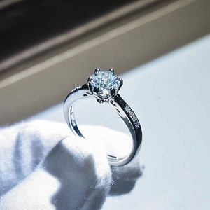 Detailed close-up of a six-prong silver ring with a brilliant round-cut center stone