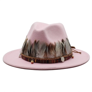 Dettaglio cappello in lana rosa con piume, nastro etnico e ciondoli in metallo