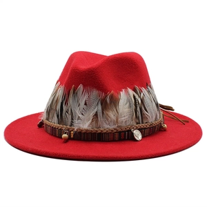 Dettaglio cappello in feltro rosso con piume naturali e decorazioni in stile etnico