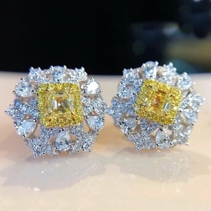 Luxe canary yellow diamond stud earrings with micro-paved white gems on a mirror surface