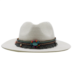 Detail of white straw hat featuring a bohemian band with turquoise and grey tassels