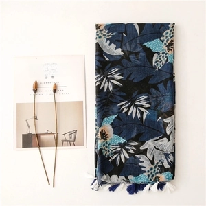 Navy blue linen-feel scarf with tropical leaf print and tassel fringe flat lay display