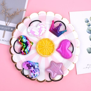 Detail of 6-piece sequin hair ties set with heart, crown, and star shapes on pink background
